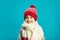 Portrait of beautiful little girl in red winter hat on blue background