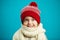 Portrait of beautiful little girl in red winter hat on blue background