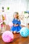 A portrait of a beautiful little girl in a studio decorated many color balloons