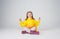 Portrait of a beautiful little girl in a yellow raincoat, sitting in a lotus relax pose on an isolated white background.