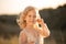 Portrait of a beautiful little princess girl in a pink dress. Posing in a field at sunset