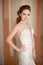 Portrait of Beautiful luxurious female model with medium brown hair in a long fashinable dress standing in the room.