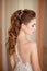 Portrait of Beautiful luxurious female model with medium brown hair in a long fashinable dress standing in the room.