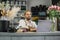 Portrait of beautiful male florist in apron working on laptop in flower store.