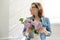 Portrait of beautiful mature woman at home with bouquet of lilac flowers. Background of home interior dining near the window