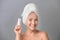 Portrait of beautiful mature woman with perfect skin holding tube of cream