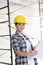 Portrait of beautiful mid adult architect wearing hardhat with blueprints