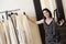Portrait of a beautiful mid adult woman selecting dress from rack in fashion boutique