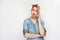 Portrait of beautiful minded young woman in casual blue denim shirt with makeup and red headband standing, talking on the phone