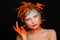 Portrait of a beautiful model with creative make-up and hairstyle using orange feathers