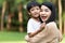 Portrait beautiful mother and child happily hugged in park. Asian family mom and child are hugging and looking at the camera, cute