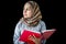 Portrait of beautiful Muslim young woman wearing hijab scarf, reading Muslim book Quran holy Koran book of Islam in her hand on