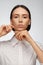 Portrait of a beautiful pacified woman in a white shirt on a light background