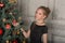 Portrait of a beautiful pensive girl in black near the Christmas tree at Christmas