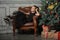 Portrait of a beautiful pensive girl in black near the Christmas tree at Christmas