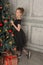 Portrait of a beautiful pensive girl in black near the Christmas tree at Christmas