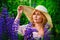 Portrait of a beautiful plump blonde in a large straw hat, a girl with a bouquet of lupines in her hands, posing in a blooming