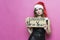Portrait of a beautiful sad, sad brunette woman in christmas hat and festive black dress holding a cardboard sign `unlucky new yea