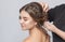 Portrait of a beautiful sensual light brown haired woman with a wedding hairstyle in a beauty salon. The hairdresser does the