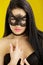 Portrait of beautiful sensual woman in black lace mask on yellow background. girl in venetian mask