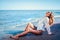 Portrait of beautiful sexy caucasian sunbathed woman in sunglasses with long hair in swimsuit lying on summer beach