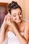 The portrait of the beautiful smiling bride putting the earrings on.