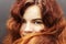 Portrait of a beautiful smiling red-haired young teenage girl close-up. Cute girl with bright red long hair on a dark background.