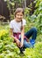 Portrait of beautiful smiling teenage girl sitting in garden and spudding garden bed