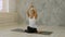 Portrait of beautiful smiling young woman working out indoors in loft interior doing Marichyasana pose with namaste