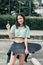 Portrait beautiful sportive Asian female skater wearing hipster clothes with lollipop, smiling with happiness, holding skateboard