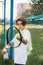 Portrait of a beautiful teenage boy standing with a tennis racket and a ball in his hands. Tennis player resting after