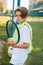 Portrait of a beautiful teenage boy standing with a tennis racket and a ball in his hands. Tennis player resting after