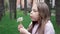 Portrait of a beautiful teenage girl blowing on the ripened dandelion in a spring or summer park. Slow motion video