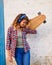 Portrait of a beautiful urban skater young woman holding a longboard