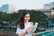 Portrait of beautiful Vietnamese girl standing and reading a book in wind with blur city background. Happy reader in college