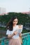 Portrait of beautiful Vietnamese girl standing and reading a book in wind with blur city background. Happy reader in college