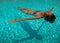 portrait of a beautiful white woman enjoying a relaxing calm time swimming in the transparent water of a pool in a sunny day of