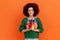 Portrait of beautiful woman with Afro hairstyle wearing green casual style sweater holding in hands
