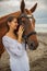 Portrait of beautiful woman and brown horse. Caucasian woman hugging and stroking horse. Love to animals. Beach in Bali, Indonesia