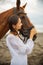 Portrait of beautiful woman and brown horse. Caucasian woman hugging and stroking horse. Love to animals. Beach in Bali, Indonesia