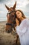 Portrait of beautiful woman and brown horse. Caucasian woman hugging and stroking horse. Love to animals. Beach in Bali, Indonesia