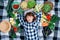 Portrait beautiful woman farmer lying on a plaid among fresh organic vegetables. Top view