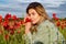 Portrait of a beautiful woman on flowering poppy field. Summer holidays on nature. Girl on poppies meadow with poppys