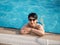 Portrait of a beautiful woman in glasses in the pool at the side. Female on vacation smiling and looking at the camera