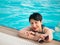 Portrait of a beautiful woman in glasses in the pool at the side. Female on vacation smiling and looking at the camera