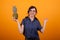 Portrait of beautiful woman with glasses smiling at the camera and holding a delicious ananas in studio over yellow