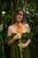 Portrait of beautiful woman with heliconia flowers in jungle. Caucasian woman in tropical rain forest, wearing green dress. Nature