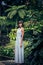 Portrait of beautiful woman posing among blooming asian flowers on Bali island, Indonesia.