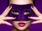 Portrait of a beautiful  woman with purple nails and violet theatre mask on face