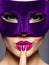 Portrait of a beautiful woman with purple nails and violet theatre mask on face